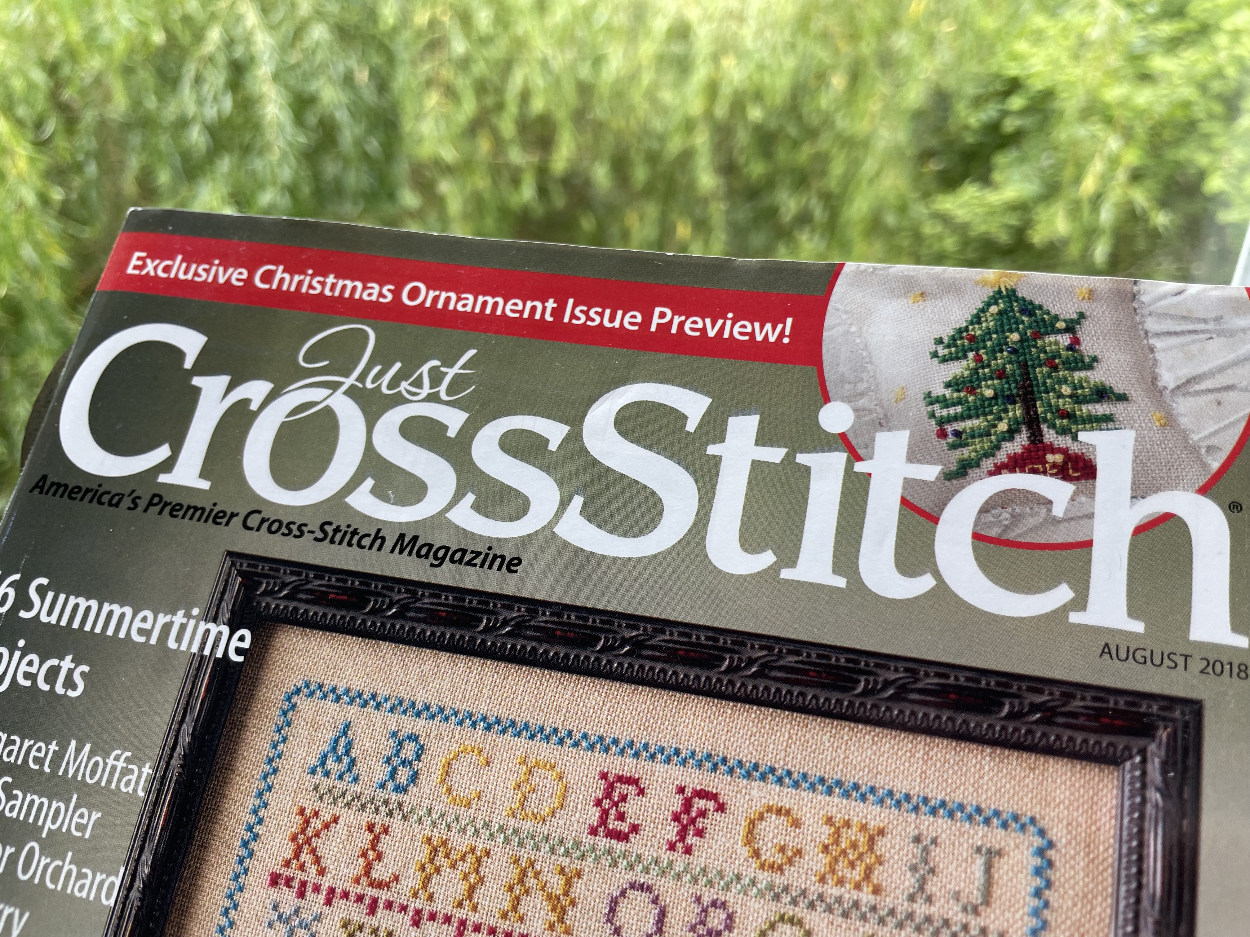 A picture of cross stitch magazine cover featuring a Christmas tree pattern designed by cross stitch sanctuary on the front cover